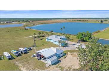 Stunning aerial view of a lakefront property with a spacious home and a large outbuilding for RV parking at 29527 Leah Rd, Punta Gorda, FL 33982