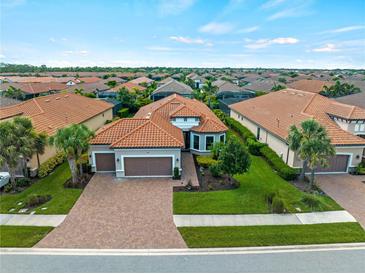 Beautiful Mediterranean-style home featuring a tile roof, three-car garage, brick driveway and lush landscaping at 5364 Salcano St, Sarasota, FL 34238