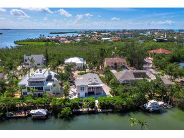 Waterfront homes with private docks nestled in lush greenery overlooking the bay in a sunny, tropical locale at 663 Penfield St, Longboat Key, FL 34228