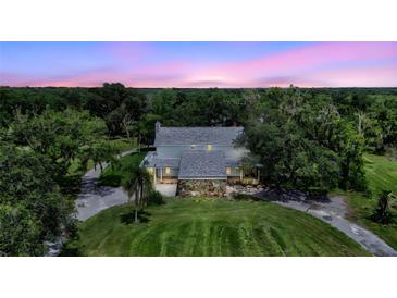 Charming two-story home featuring a stone foundation and inviting covered porch, surrounded by lush greenery at 6633 Old Ranch Rd, Sarasota, FL 34241