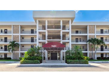 Condo building featuring a covered entrance, well-maintained landscaping and palm trees at 7461 W Country Club N Dr # 206, Sarasota, FL 34243