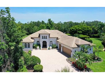 Stunning home featuring a tile roof, three car garage, and beautiful landscaping at 13203 Lost Key Pl, Lakewood Ranch, FL 34202