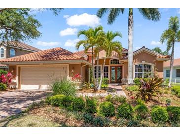 Beautifully landscaped single-Gathering home featuring a clay tile roof and attached two-car garage at 7521 Aralia Way, Seminole, FL 33777