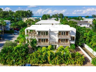 Beautiful multi-story building with balconies surrounded by lush, tropical landscaping, and ocean views at 804 N Shore Dr, Anna Maria, FL 34216