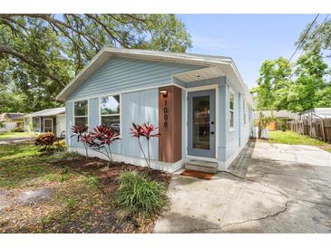 Charming light blue home featuring a landscaped yard and inviting front door with vertical wood accent at 1008 37Th W St, Bradenton, FL 34205