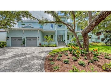 A bright, light blue two-story home with a paver driveway and an oversized 2-car garage at 1076 Toc0Baga, Sarasota, FL 34234