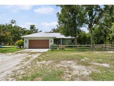 Charming single-story home featuring a metal roof and well-maintained front yard with a wooden fence at 15780 Wilson Rd, Sarasota, FL 34240