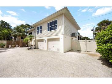 Beige two-story home with two-car garage, crushed gravel driveway and tropical landscaping at 1801 Highland Rd, Osprey, FL 34229