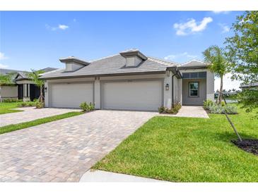 Charming single-story home with a well-manicured lawn and a three-car garage on a sunny day at 18039 Cherished Loop, Bradenton, FL 34211