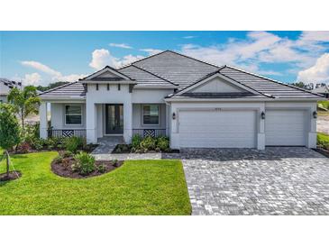Charming one-story home with a tile roof, manicured lawn, paver driveway, and three car garage at 3512 Cross Creek Pkwy, Parrish, FL 34219