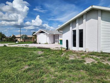 Exterior view of a white stucco home with green lawn and bright blue sky at 4354 Rock Creek Dr, Port Charlotte, FL 33948