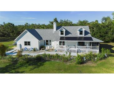 Inviting two-story home featuring a charming front porch and lush, landscaped surroundings at 4888 Old Ranch Rd, Sarasota, FL 34241