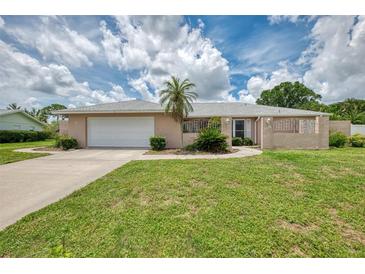 Charming one-story home with a well-manicured lawn, mature landscaping and a two-car garage at 5124 Palm Aire Dr, Sarasota, FL 34243