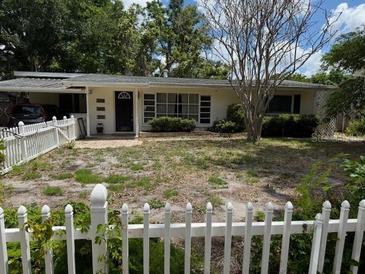 Quaint single-story home with a white picket fence and mature trees in the front yard at 2451 Loma Linda St, Sarasota, FL 34239