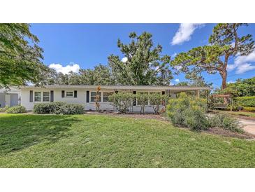 Charming single-story home featuring a well-manicured lawn and welcoming front entrance with lots of shade trees at 2462 Hyde Park St, Sarasota, FL 34239