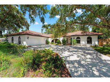 Beautiful home exterior with mature landscaping, red tile roof, and a spacious driveway at 2504 Tanglewood Dr, Sarasota, FL 34239