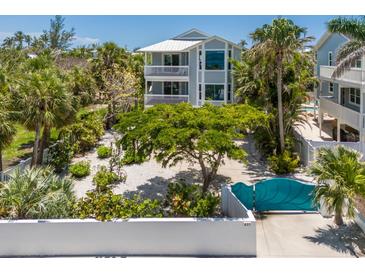 Beautiful two-story home with balconies, lush landscaping, and a unique turquoise gate at 401 N Bay Blvd, Anna Maria, FL 34216