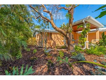 Inviting backyard featuring tropical foliage, garden beds, and a charming swing for relaxing outdoors at 6806 Palm Dr, Holmes Beach, FL 34217