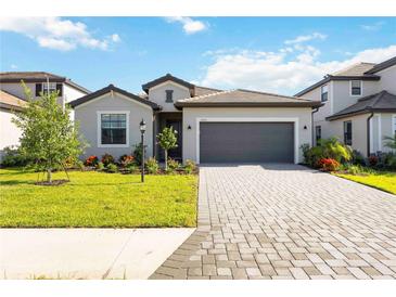 Beautiful single-story home featuring a paver driveway, a two-car garage, and lush landscaping at 15115 Oxford Grey Dr, Bradenton, FL 34211