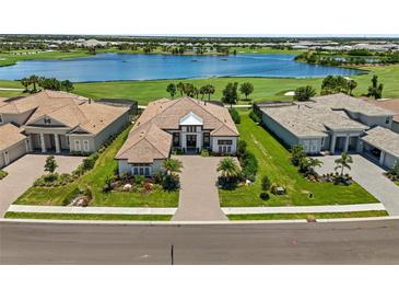 Stunning aerial view of a home with lush landscaping and a beautiful lake backdrop in a golf community at 3936 Santa Caterina Blvd, Bradenton, FL 34211
