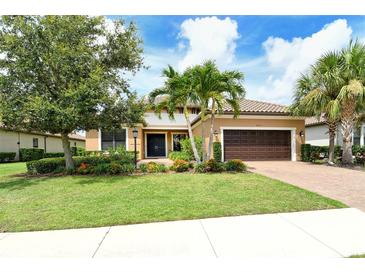 Beautiful single Gathering home featuring a tile roof, brick driveway, and lush landscaping with palm trees at 4916 Tivoli Run, Bradenton, FL 34211
