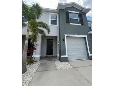 Two-story townhome featuring a one-car garage, neutral paint, and a well-maintained front yard with a palm tree at 8995 Milestone Dr, Sarasota, FL 34238