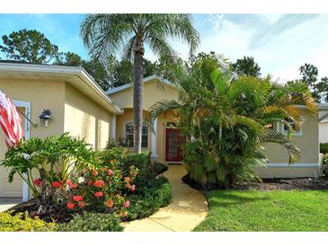 Charming home featuring a well-manicured lawn, tropical plants, and inviting walkway to the front door at 12113 Whistling Way, Lakewood Ranch, FL 34202