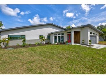 A modern home featuring a well-manicured lawn, contemporary architectural design, and a striking red door at 3636 Mineola, Sarasota, FL 34239