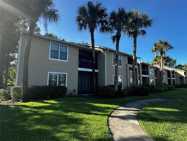 Inviting two-story condo building featuring mature palm trees and a well-manicured lawn at 4002 Crockers Lake Blvd # 11, Sarasota, FL 34238