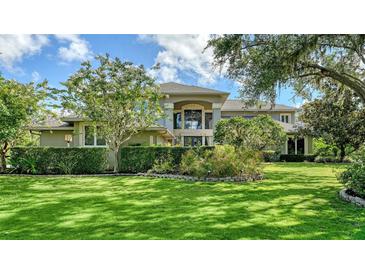 Stately home featuring manicured lawn, lush landscaping, and a grand entrance with large windows and decorative trees at 6905 Pine Valley St, Bradenton, FL 34202