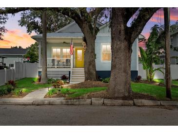 Charming blue two-story home with a bright yellow front door and inviting front porch and mature trees at 112 17Th E St, Bradenton, FL 34208
