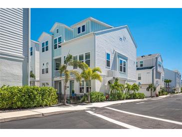 Beautiful three-story home with light blue accents and tropical landscaping in a vibrant community at 2400 Ezzell Ct, Sarasota, FL 34237