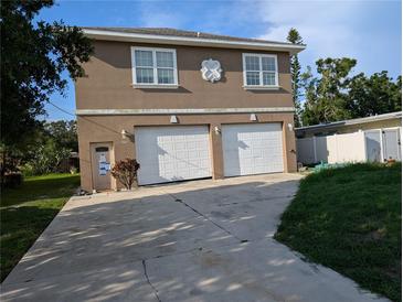 Two-story home with a double garage and a light brown facade in need of renovation at 3006 Hawthorne St, Sarasota, FL 34239