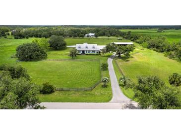 Expansive aerial view of a beautiful white home on lush green property with pond, barn, and surrounding mature trees at 3100 Lena Ln, Sarasota, FL 34240