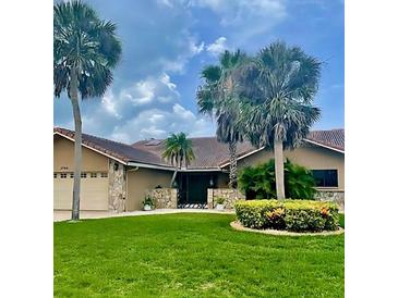 Charming single-story home with a lush lawn, stone accents, and beautiful palm trees at 3764 Torrey Pines Blvd, Sarasota, FL 34238