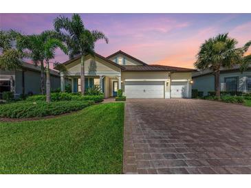 Beautiful single-story home featuring a three-car garage, lush landscaping, and a brick paver driveway at 7781 Grande Shores Dr, Sarasota, FL 34240