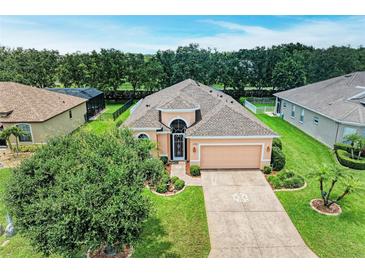 Well-maintained home features a lush lawn, landscaped beds, and a decorative driveway at 12851 24Th Street E Cir, Parrish, FL 34219