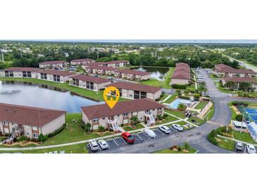 Scenic aerial view of a condo community with lush landscaping, lake, swimming pool, and tennis courts at 25100 Sandhill Blvd # V202, Punta Gorda, FL 33983