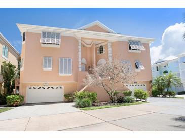 Charming two-story peach home with two-car garage and well-maintained landscaping under a clear blue sky at 3954 Hamilton Club Cir # 14, Sarasota, FL 34242