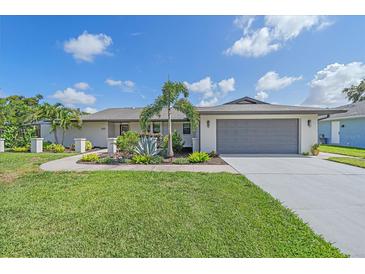 Charming single-story home featuring a gray roof, a two-car garage, and lush landscaping at 4396 Pasadena Cir, Sarasota, FL 34233