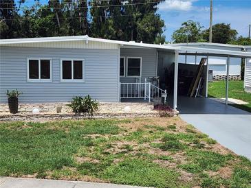 Charming single-story home featuring light-grey siding, a covered carport, and a cozy front porch at 5316 Chateau Ln, Bradenton, FL 34207