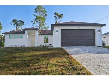 New construction home boasting a fresh white facade, dark roof, and manicured landscaping at 5386 Easter Ter, North Port, FL 34286
