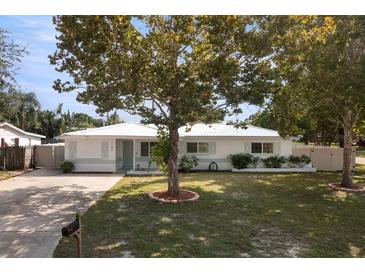 Charming one-story home featuring a well-manicured lawn, mature trees and light blue accents at 6180 42Nd N Ave, St Petersburg, FL 33709