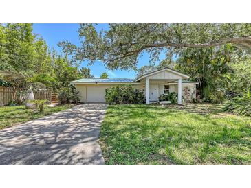 Inviting single-story home with a lush front yard, mature trees, and a cozy, covered front porch at 626 46Th St, Sarasota, FL 34234