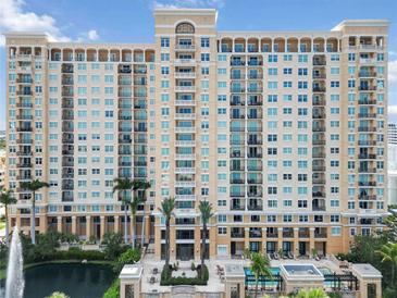 Luxury high-rise condo with a fountain, pool, and palms against a blue sky at 750 N Tamiami Trl # 1005, Sarasota, FL 34236