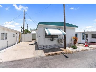 Charming mobile home featuring a teal awning, white lattice trim, and well-kept landscaping at 10315 Cortez W Rd # 60-4, Bradenton, FL 34210