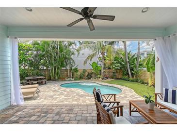 Inviting outdoor space featuring a kidney-shaped pool, tropical landscaping, and a covered patio with comfortable seating at 1738 Siesta Dr, Sarasota, FL 34239