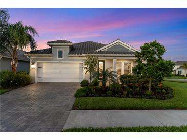 Charming single-Gathering home featuring a two-car garage, paver driveway, lush landscaping, and twilight sky at 2586 Wild Cherry Path, Sarasota, FL 34240
