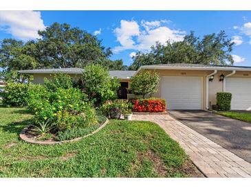 Charming home featuring a well-manicured lawn, garden, brick pathway, and a one-car garage at 6916 W Country Club N Dr # 9B, Sarasota, FL 34243