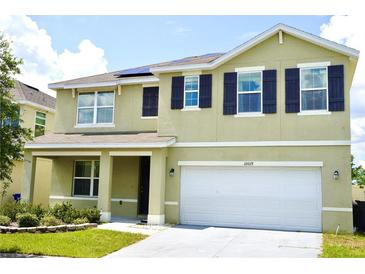 Two-story home featuring a two-car garage, dark shutters, and solar panels on the roof at 10019 Geese Trail Cir, Sun City Center, FL 33573